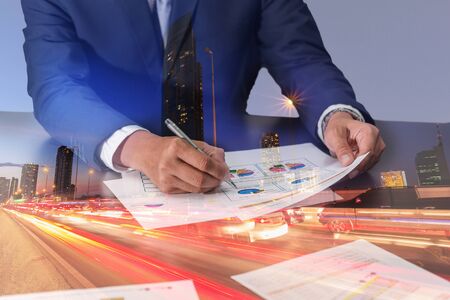 Double exposure of businessman review charts, light trails on the street and urban at dusk, night as business and analysis concept.の写真素材