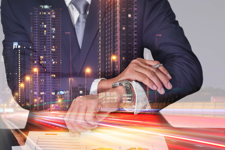 Double exposure of businessman look the watch, light trails on the street and urban in the night as appointment and business concept.の写真素材