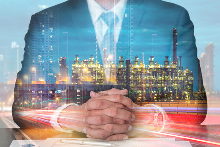 Double exposure of businessman fingers crossed and sit down, light trails on the street and urban, Electric generating factory industry in the night as meeting, commitment, business and energy concept.の写真素材