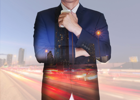 Double exposure of businessman stand up and think idea about business, light trails on the street and urban at dusk, night as thoughtful concept.の写真素材