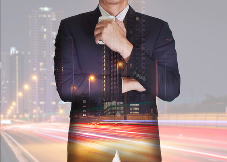 Double exposure of businessman stand up and think idea about business, light trails on the street and urban in the night as thoughtful concept.の写真素材