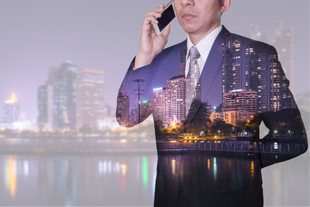 Double exposure of businessman calling with smartphone, lake and urban in the night as business, technology, communication and telecommunication concept.の写真素材