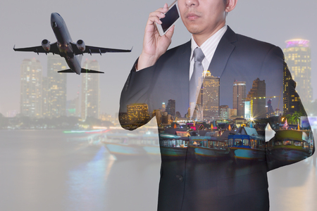 Double exposure of businessman calling with smartphone, takeoff of airplane, city, urban and river in the night as business, technology, telecommunication and air transportation concept.の写真素材