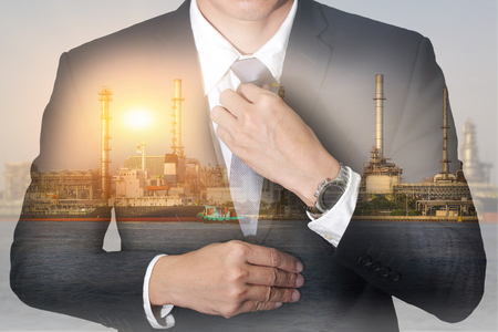 Double exposure of businessman held necktie dress to look good, oil fuel, Electric generating factory, plant near the river and sunset  as business, industrial and energy concept.の写真素材