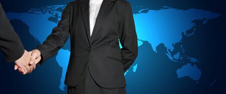 Businesswomen handshake on light blue poly world map background as business, commitment, welcome, global concept.の写真素材
