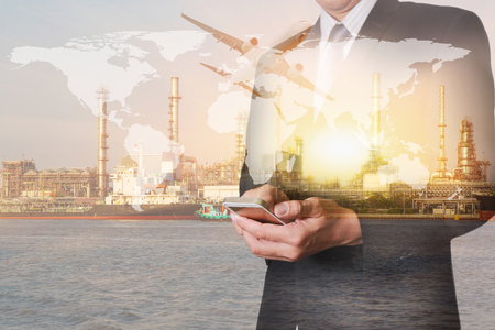 Double exposure of businessman hold smartphone, airplane flying, oil refinery industry plant and river at sunset as business, technology, communication, transportation, energy and industrial concept.の写真素材