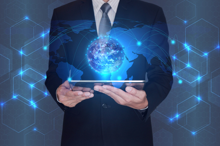 Double exposure of Businessman hand hold tablet and digital world on hexagon and light blue abstract tech innovation background as businessの写真素材