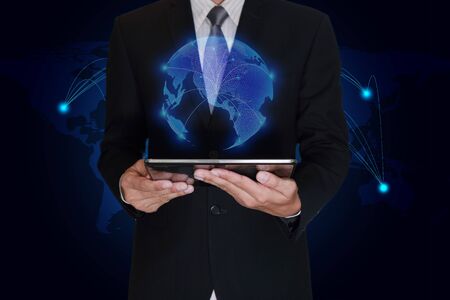 Businessman hand hold tablet and light blue polygon glowing technolgoy world map as business, technology, innovation and globalization concept.の写真素材