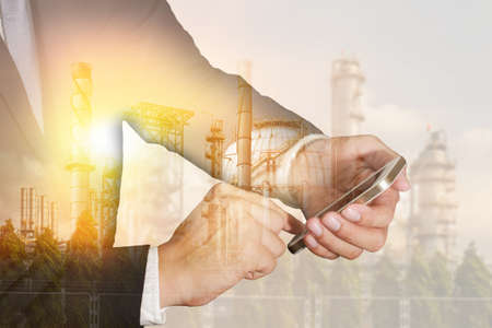 Double exposure of businessman use smartphone, oil fuel, Electric generating factory, plant and...