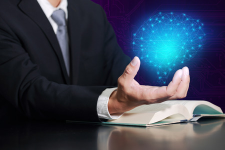 Businessman hand hold the glowing blue polygon brain on purple circuit background as business, innovation, future, brainstorm, idea, control and technology concept.の写真素材