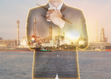 Double exposure of businessman stand up and think idea about business, oil fuel, Electric generating factory, plant, airplane and sunset as business, meeting, Learning and industrial concept.の写真素材