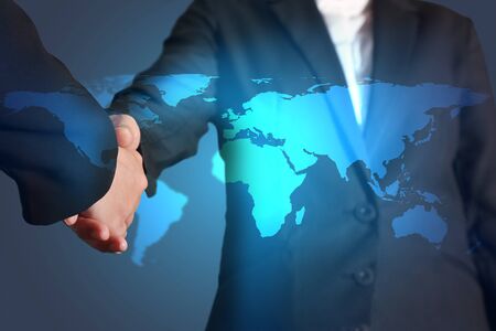 Double exposure of handshake and glowing blue world map background as businessの写真素材