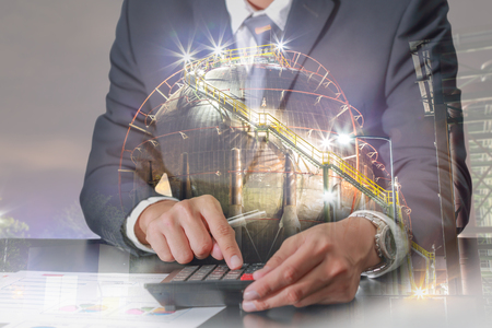Double exposure of businessman working with calculator and large chemical tank in the night as business, Worker, Calculation, industrial and energy conceptの写真素材