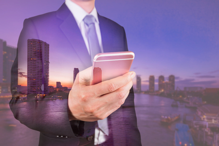 Double exposure of businessman use smartphone, communication 4G 5G node networking telephone cellsite, cityscape, urban and river in the night as business, technology and telecom conceptの写真素材