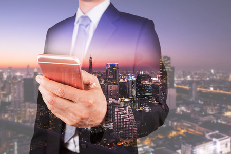 Double exposure of businessman use smartphone, communication 4G 5G node networking telephone cellsite and skyline cityscape urban in the night as business, technology and telecom conceptの写真素材