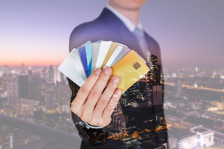 Double exposure of businessman with many credit cards as the power to spend and cityscape in the twilight or the night as busingss, investment, Shopping and payment concept.の写真素材