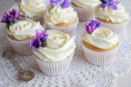 Edible purple freesia flowers on vanilla cupcakes with whipped cream frostingの写真素材