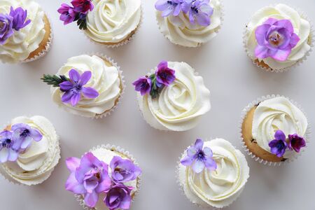 Homemade purple freesia flowers on vanilla cupcakes with whipped cream frostingの写真素材