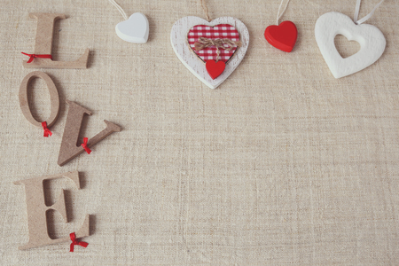 "Love" word on linen background with heart ornaments, selective focus, vintage toneの写真素材