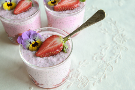 Homemade pink Chia pudding with strawberry and edible flowersの写真素材