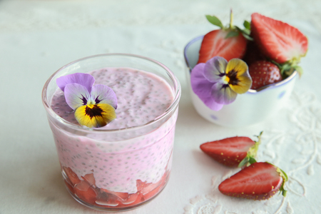 Homemade pink Chia pudding with strawberry and edible flowersの写真素材