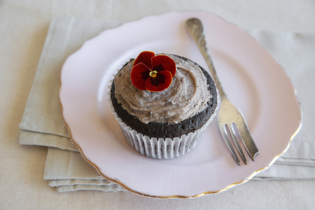 Homemade chocolate cupcakes with cookie and cream frosting and red edible flowersの写真素材