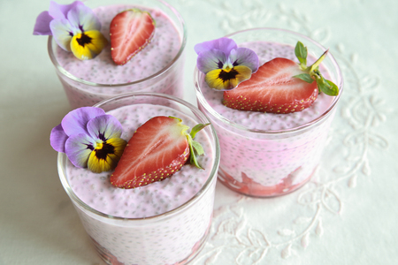 Homemade pink Chia pudding with strawberry and edible flowersの写真素材