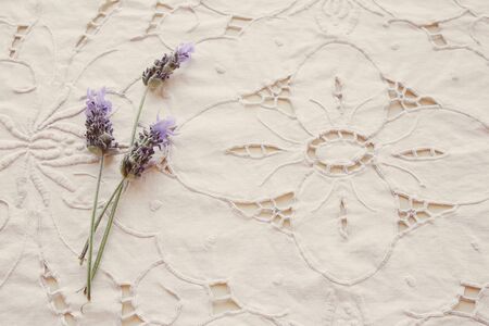 White floral linen embroidery fabric background with lavender flowers, vintage filter