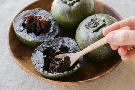 Black sapote chocolate pudding fruit in wooden plateの写真素材