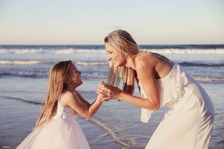 Beautiful mother and daugther laughing together on the beachの写真素材