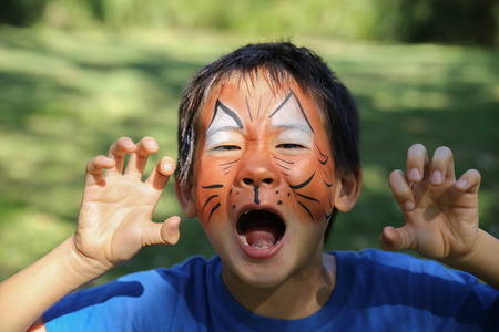 Young boy with fun face painting as a tiger