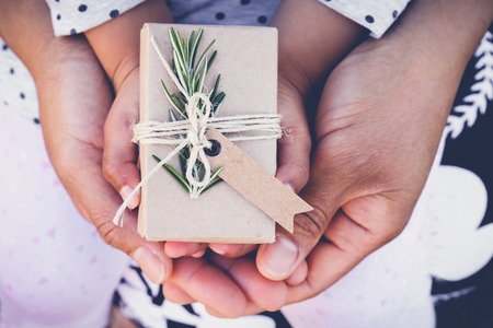 parents and child holding eco gift box with brown tag, toning backgroundの写真素材