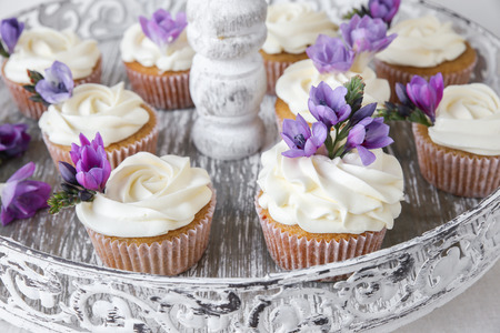 cupcakes with purple edible flowers on vintage cake stand for tea partyの写真素材