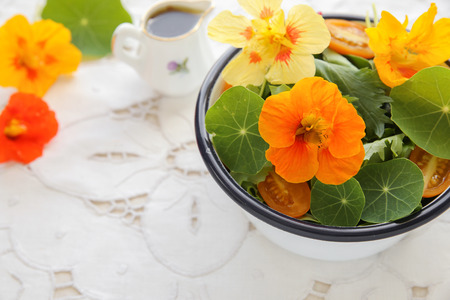 Fresh green salad with edible flowers nasturtium in vintage white dishの写真素材