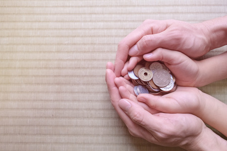 parent holding child hands with Japanese money, copy space background, saving, education conceptの写真素材