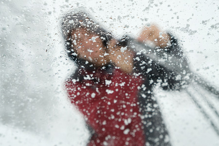 Icy windshield with blur person scraping ice off wiper ,winter driving through snow stormの写真素材