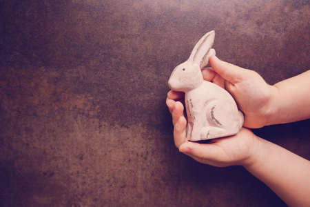 pink rabbit in hands on dark toning Easter backgroundの写真素材