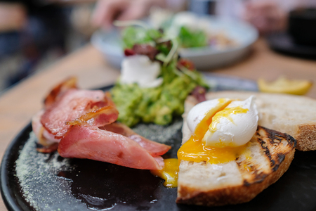 poached egg on sourdough toast with bacon and mashed avocadoの写真素材