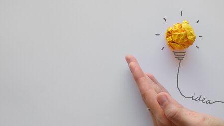 Yellow paper light bulb on hand, innovative, creative thinking business conceptの写真素材