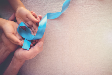 Adult and child hands holding Light blue, sky blue ribbons, toning background, Prostate Cancer Awareness and Adrenocortical carcinoma awarenessの写真素材