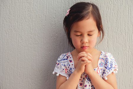 asian little girl praying with eyes closedの写真素材