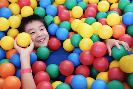 Asian boy having fun in ball pit, indoor playの写真素材