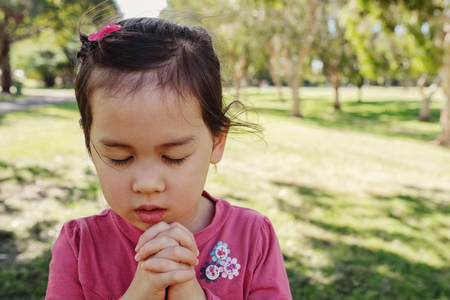 little multiethnic girl praying in the park, kid, child pray conceptの写真素材