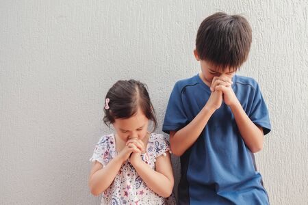 asian boy and girl praying with eyes closed