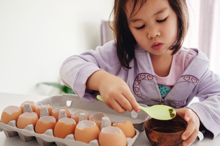 Mixed Asian girl planting seeds into eggshells, eco gardening,  montessori, education, reuse conceptの写真素材
