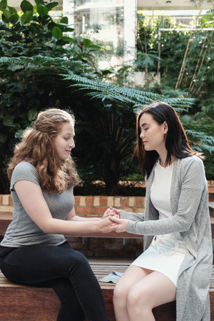 Young multicultural women holding hands while praying