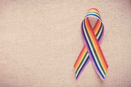 Hands holding gay pride rainbow ribbon for LGBT awarenessの写真素材
