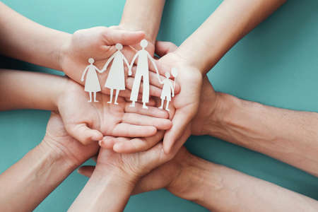 Adult and children hands holding paper family cutout, family home, foster care, homeless charity support concept, family mental health, international day of familiesの写真素材