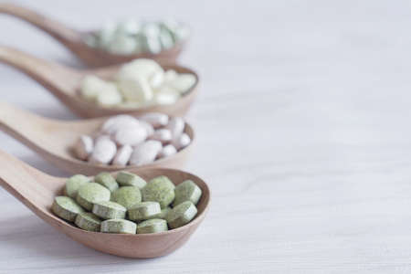 Natural cruciferous vegetables and alternative herbal tablet pills in wooden spoons, keto diet dietary supplements for healthy gutの写真素材