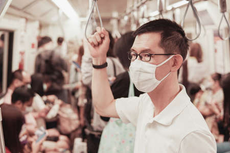 Middle aged Asian man wearing glasses and medical face mask on public train,  Wuhan coronavirus...
